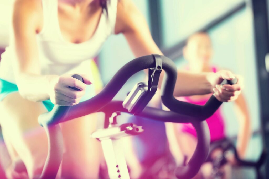 Spinning class with woman dressed in turquoise and white on the front bike.