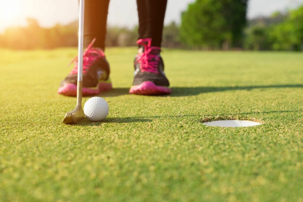 Golfer with pink and black shoes taking the shot on the golf course.