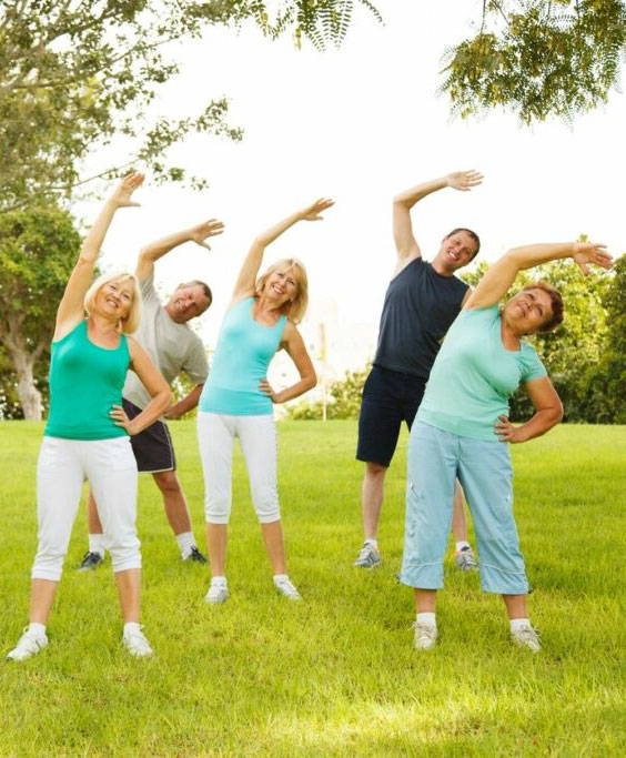 Group workout session outside with five people doing side stretches in a green park.